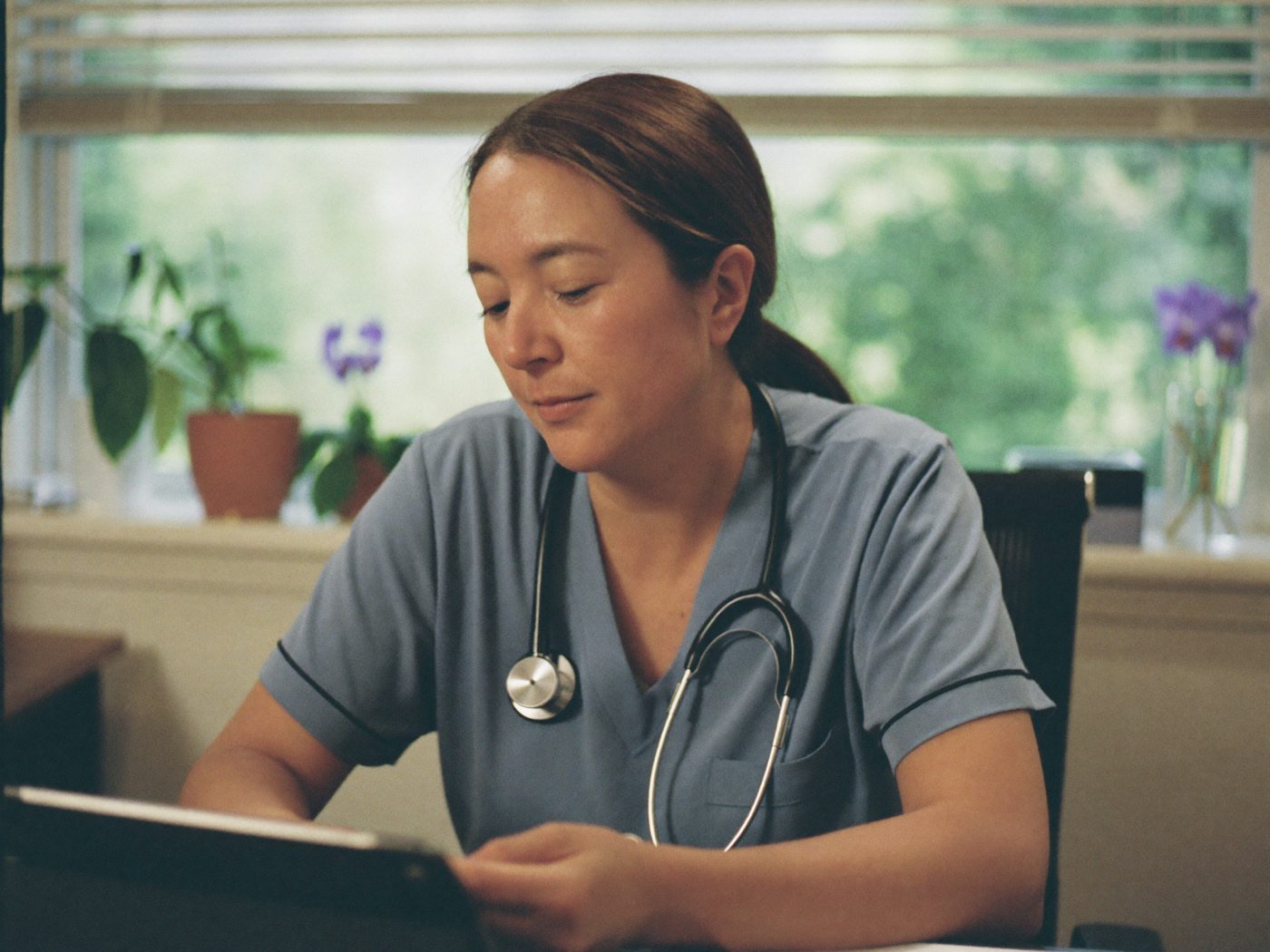 A doctor reading attentively at a desk in a calm clinic office